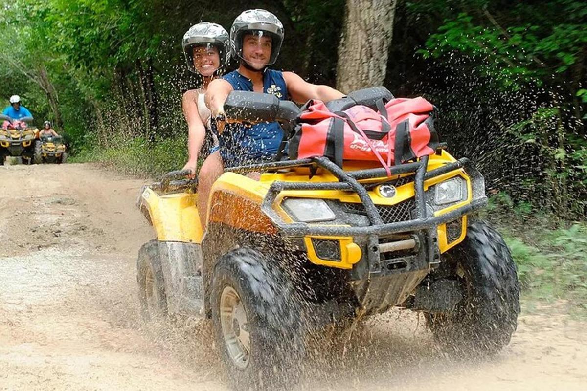 due persone che viaggiano su un veicolo a quattro ruote nello sporco