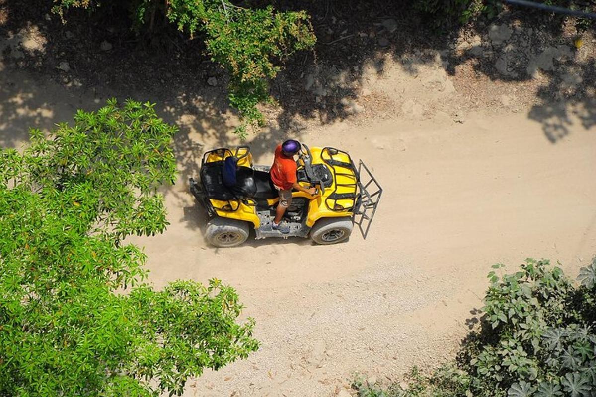 una persona conduint un quad groc a la platja