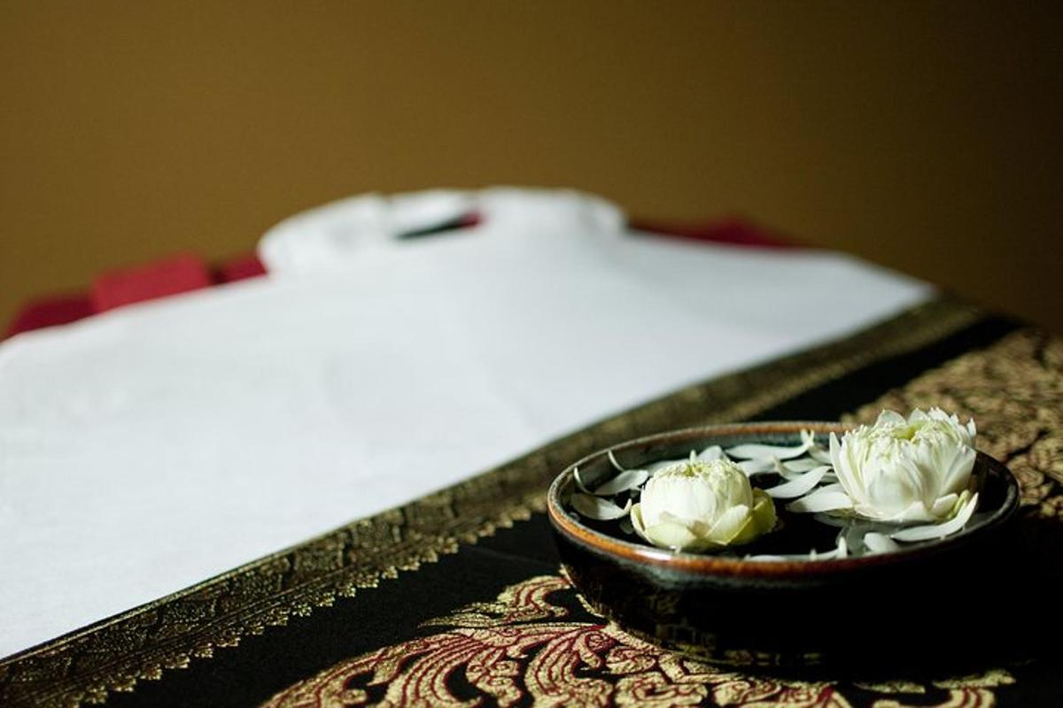 uma tigela de flores em uma mesa ao lado da cama