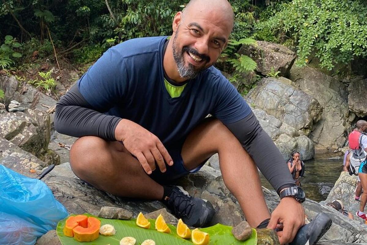 ein Mann, der mit einem Teller Essen auf einem Felsen sitzt