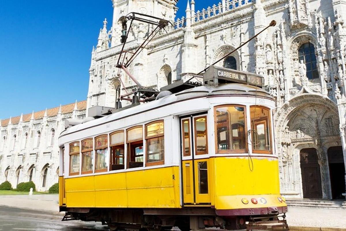 um bonde amarelo e branco em frente a um prédio