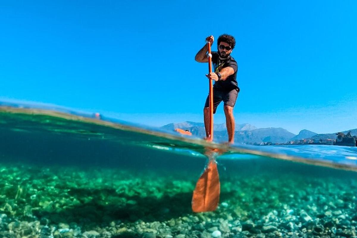 Muž stojí na paddleboardu ve vodě