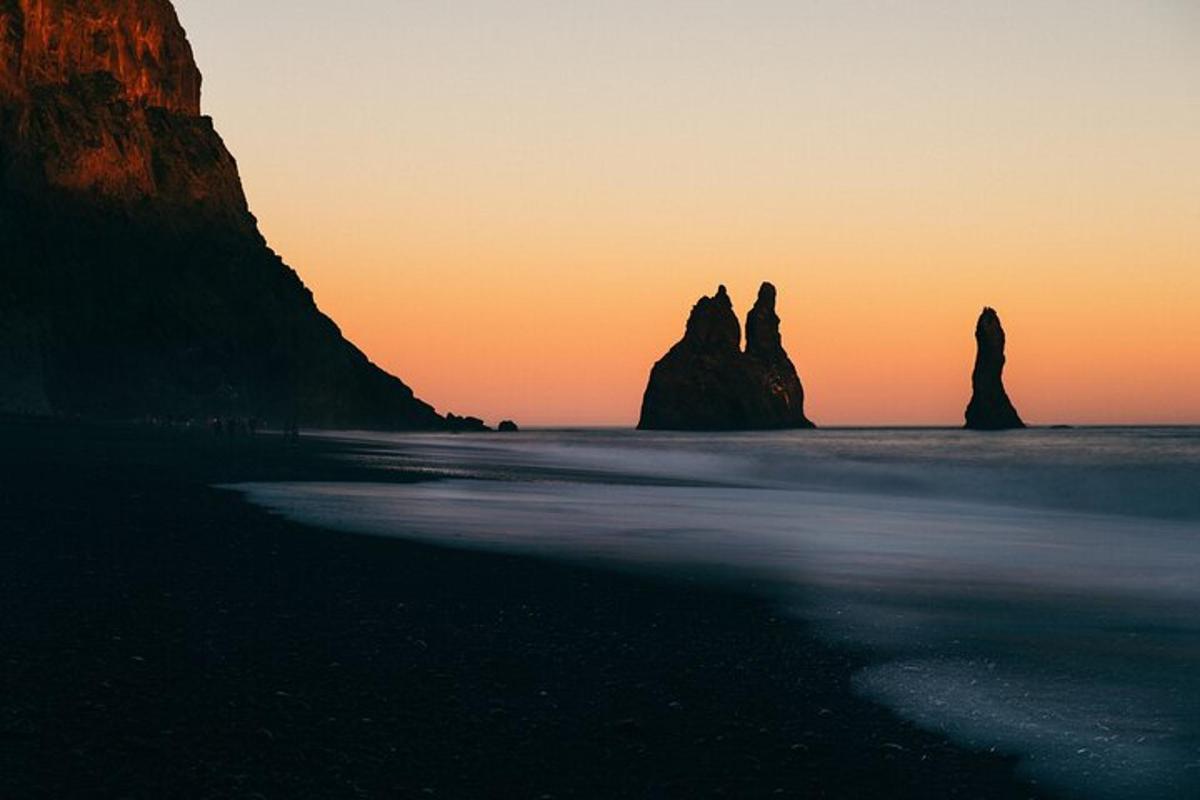 una spiaggia con rocce nell'oceano al tramonto