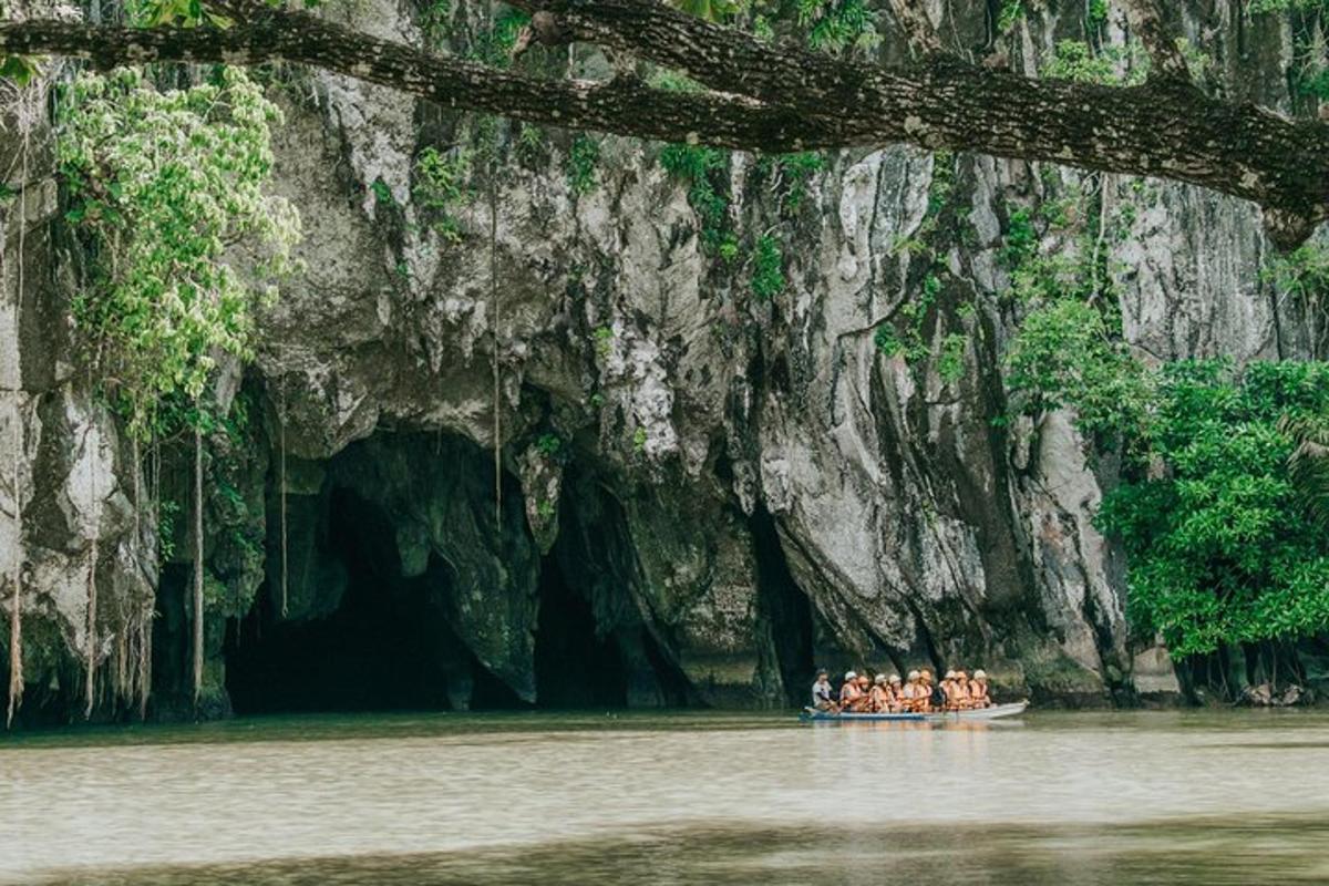 a group of people in a boat in front of a cave