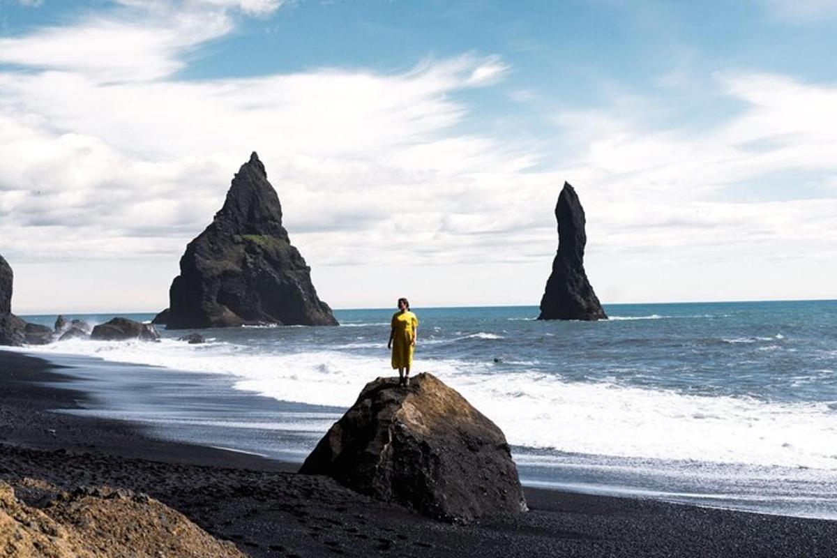 una persona in piedi su una roccia sulla spiaggia