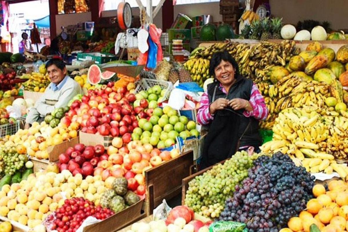 due persone sedute in un mercato con frutta e verdura