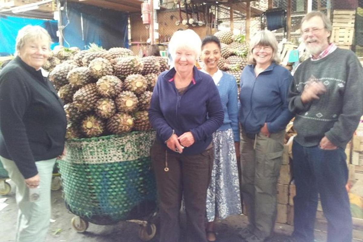 un gruppo di persone in piedi davanti a una bancarella di frutta