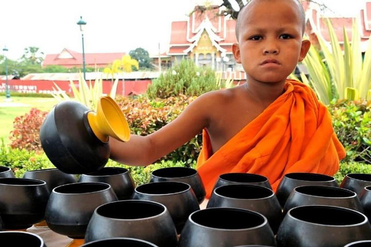 a young boy in an orange robe holding a spoon