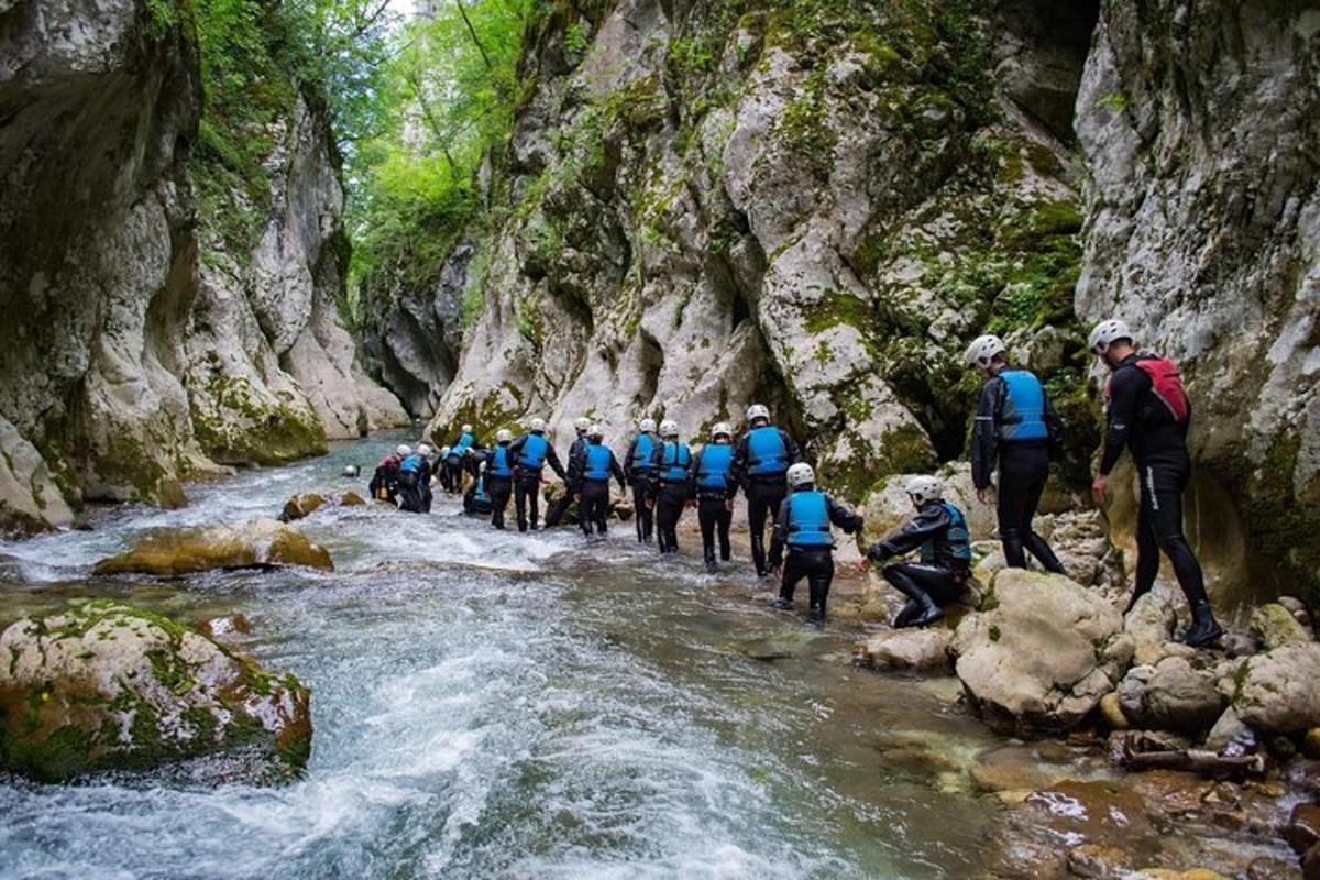 a group of people walking across a river in a canyon