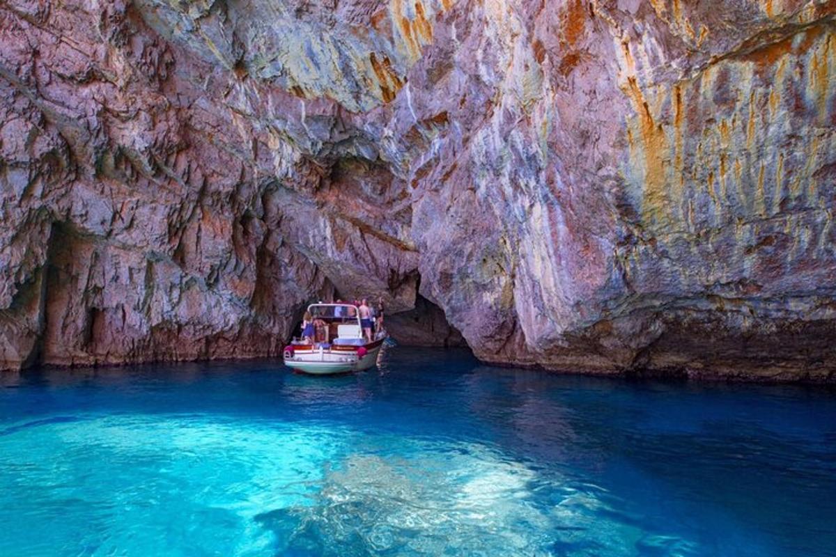 una barca in acqua accanto a una scogliera