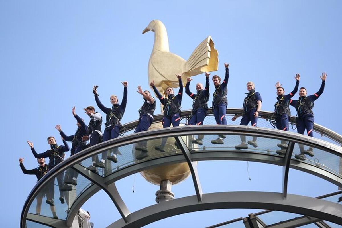 um grupo de pessoas em pé no topo de um prédio com um cisne