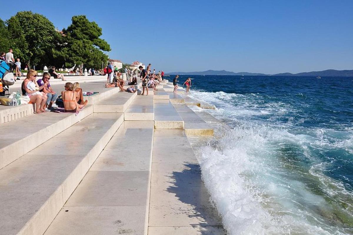 a group of people sitting on a sidewalk next to the water