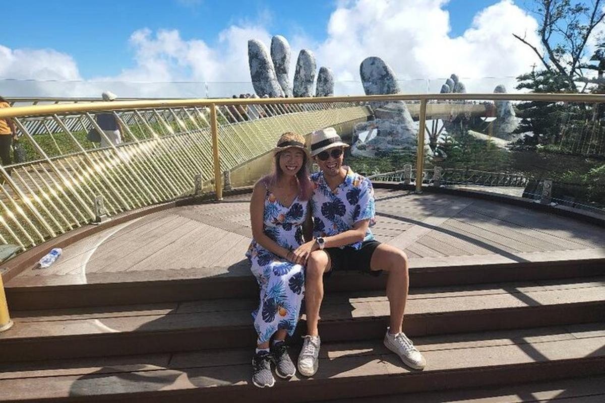 a man and woman sitting on a bench in front of a bridge