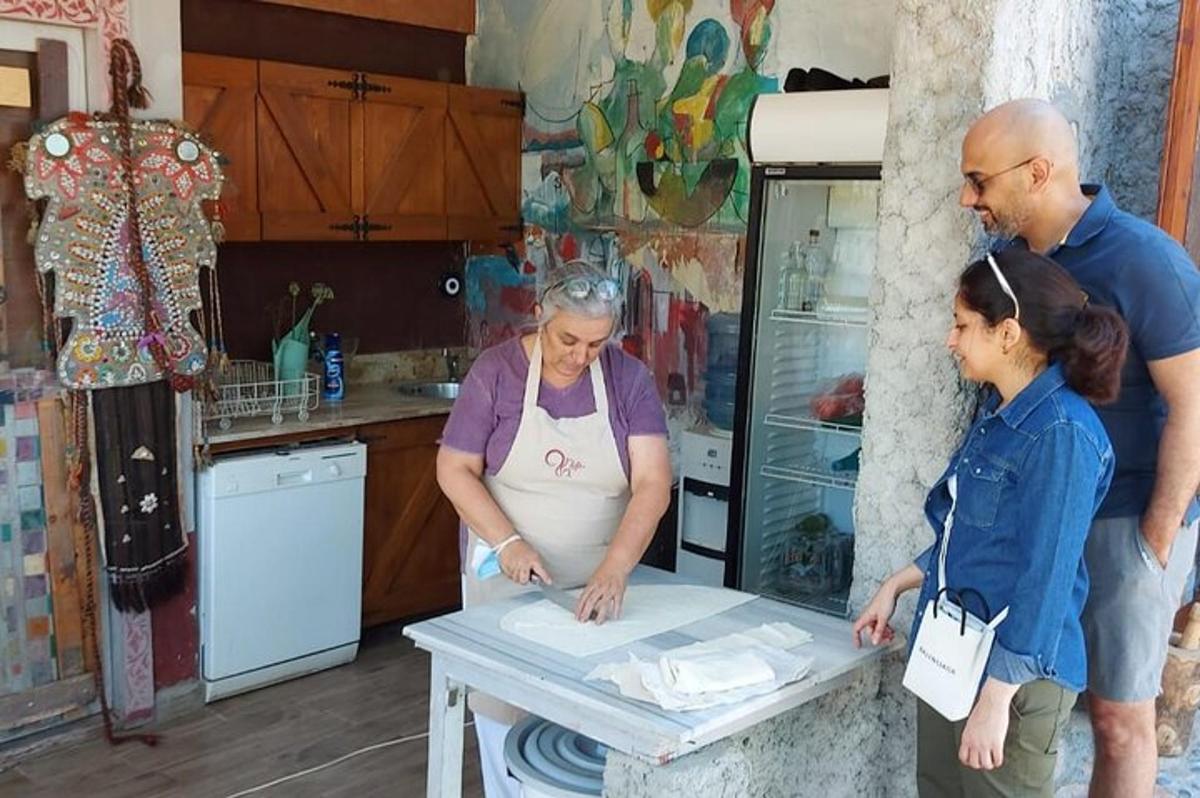 two women and a man standing in a kitchen with a table