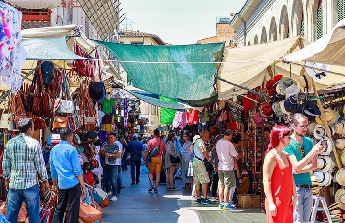 una folla di persone che camminano in un mercato con i venditori