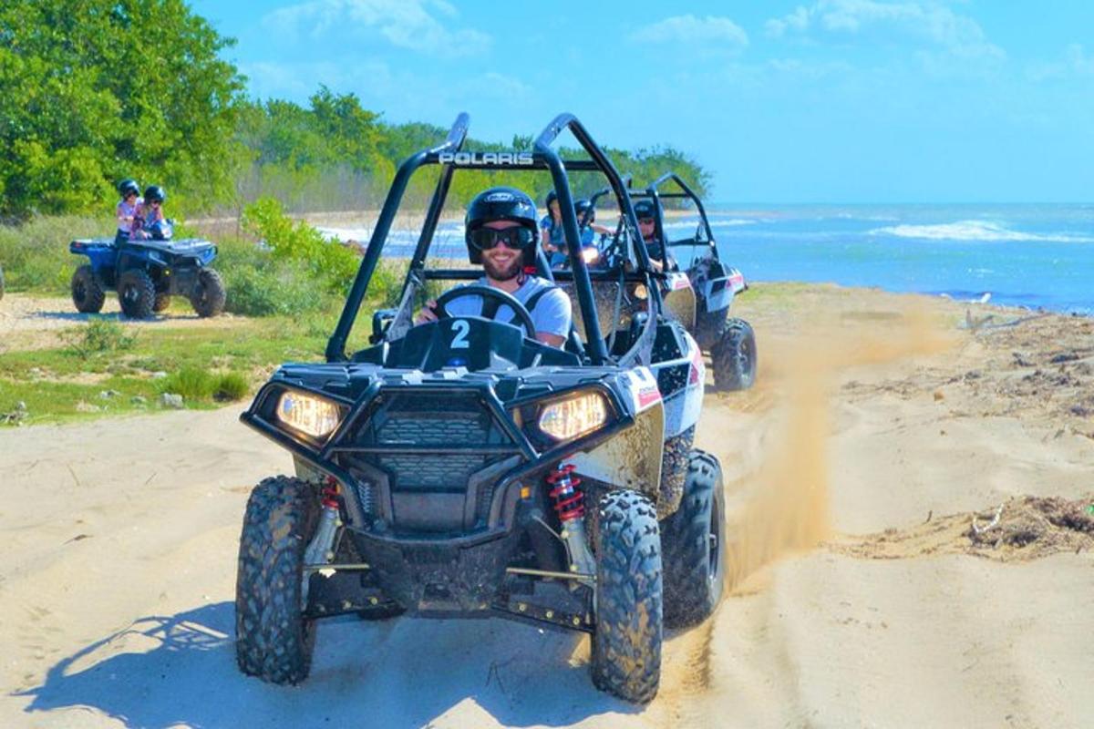 two people riding on atvs on the beach