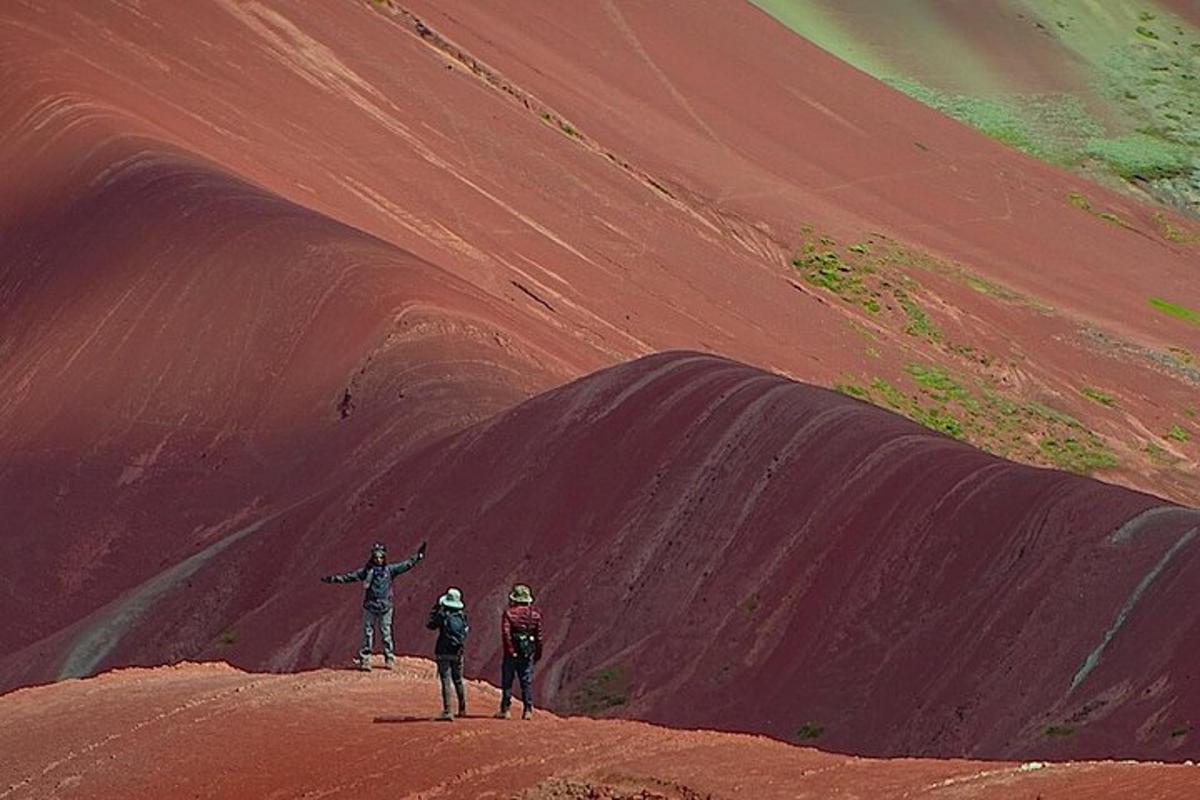 tres persones dempeus al cim d'un turó de terra