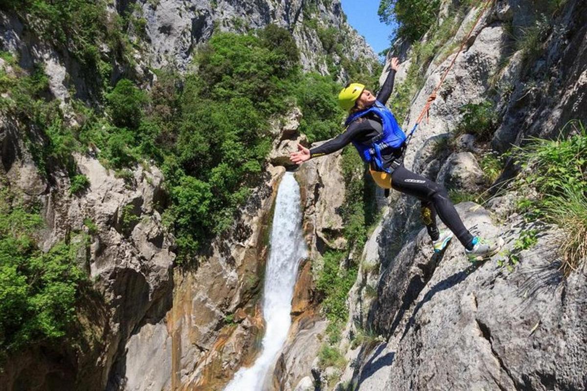 un home fent ràpel des d'una muntanya amb una cascada