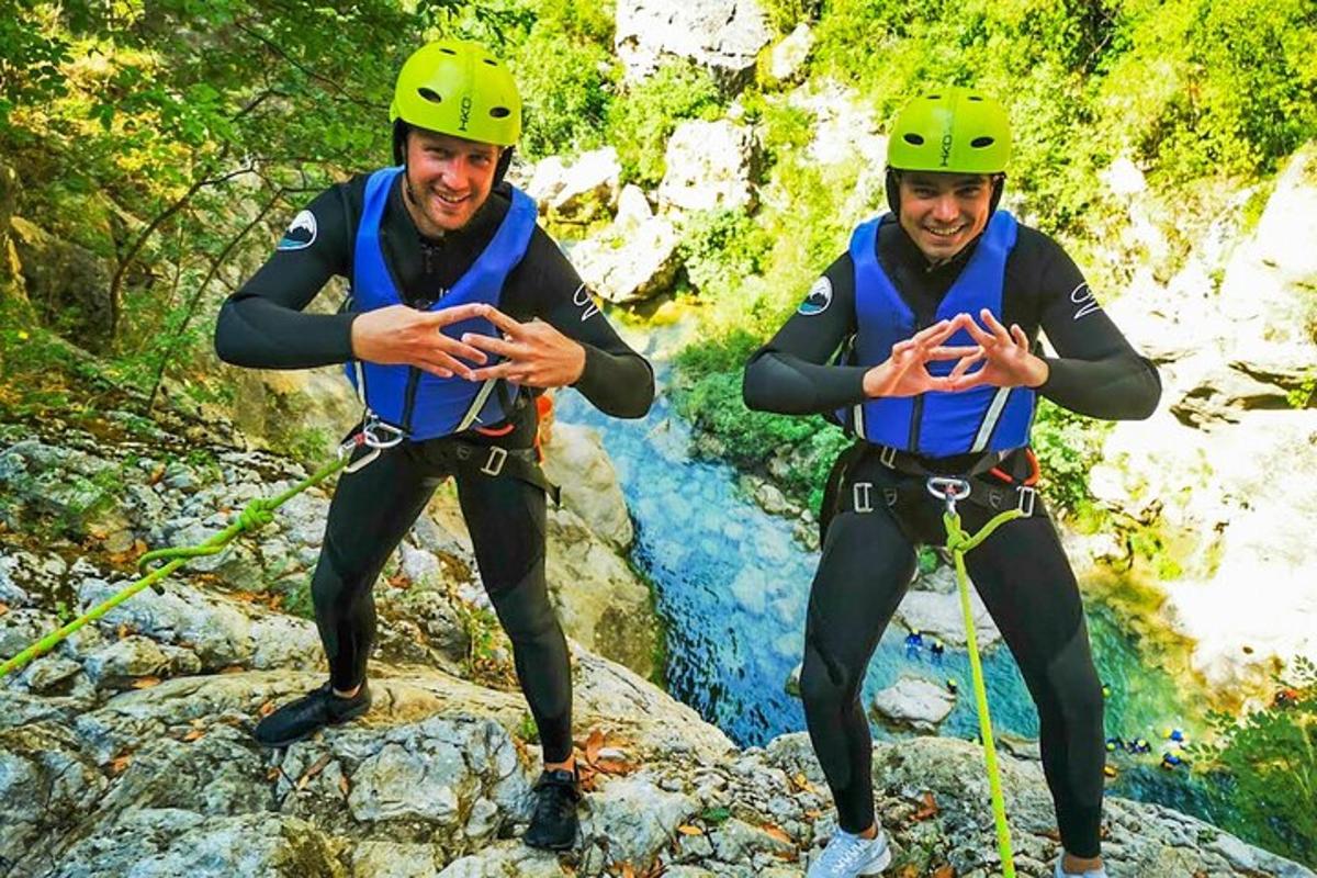 dos homes amb cascos drets sobre roques en un riu