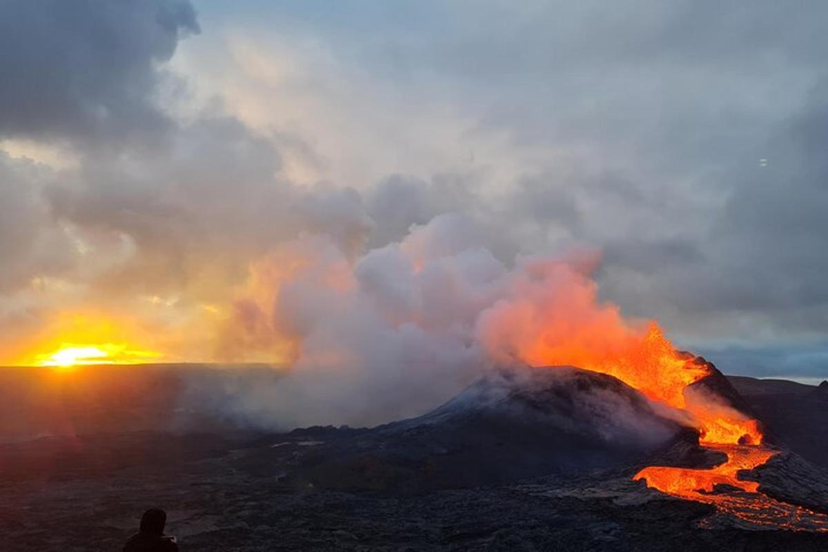 una persona in piedi di fronte a un vulcano con il fuoco