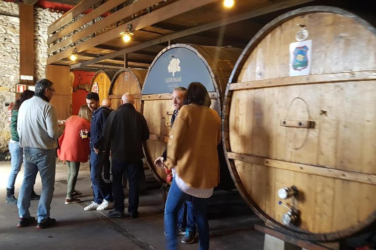 un gruppo di persone in piedi attorno a un gruppo di botti di vino