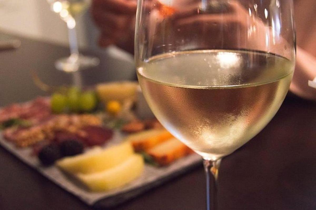 kozarec belega vina poleg krožnika hrane