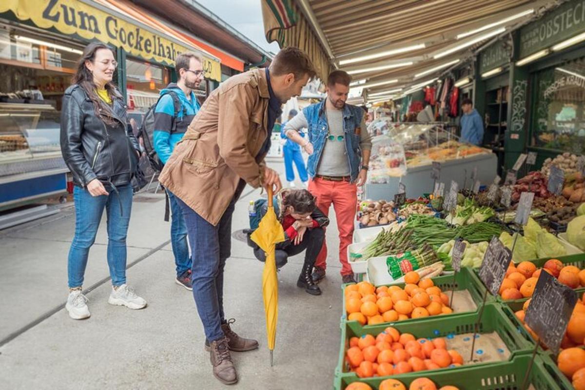 hópur fólks á markaði með manni sem heldur á regnhlíf