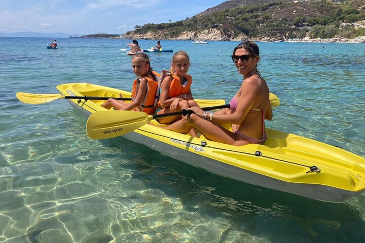 three people sitting on a yellow kayak in the water