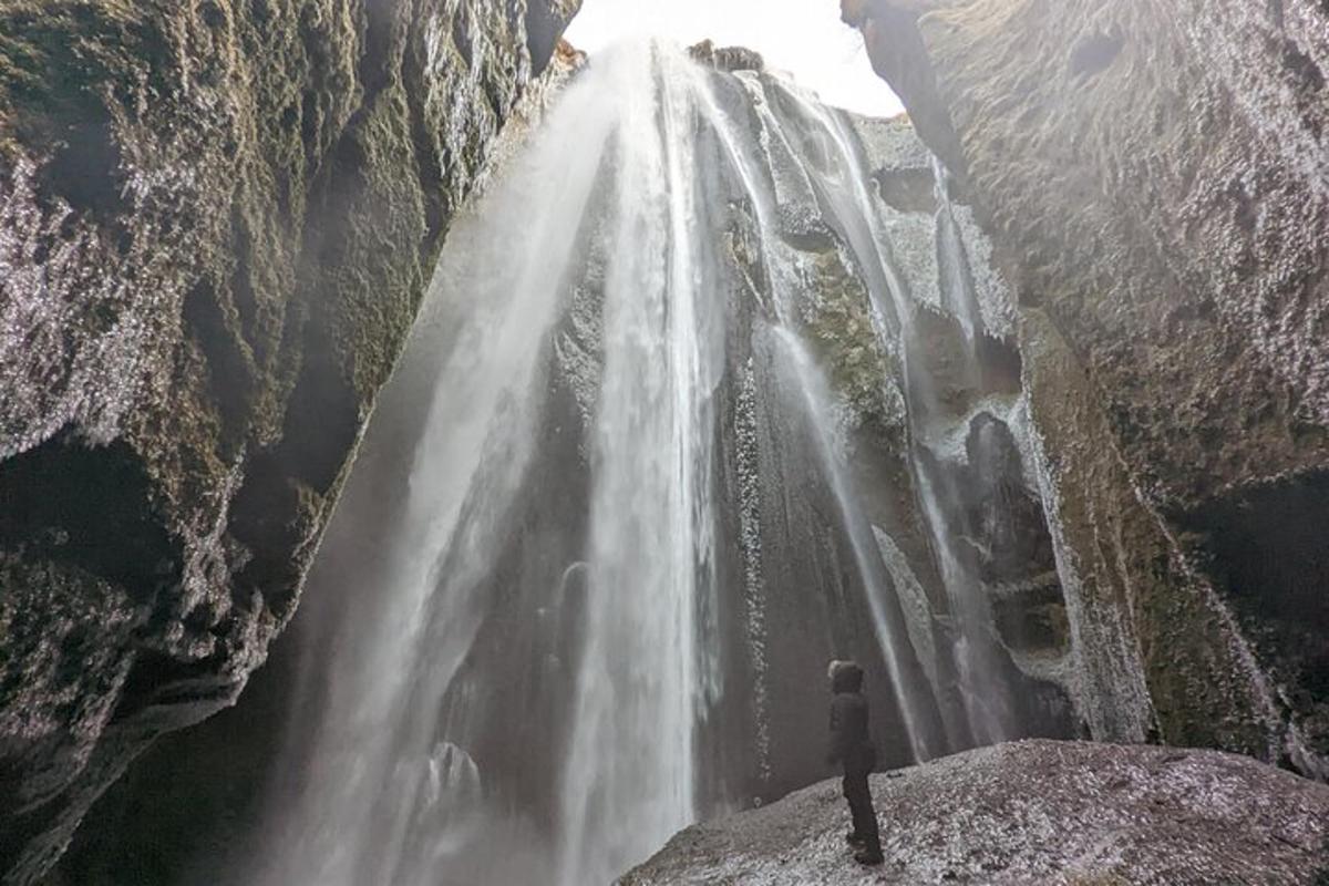 maður stendur á kletti og horfir á foss