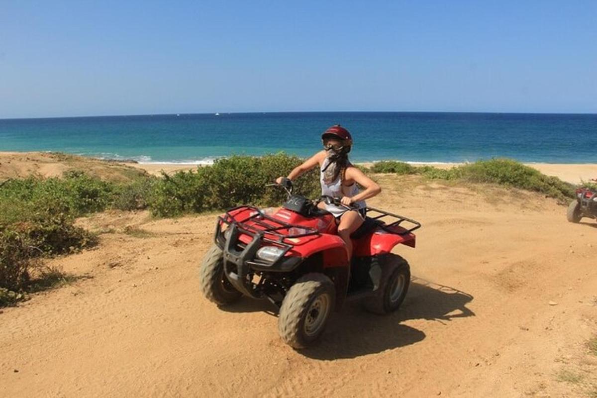 uma mulher andando de quadriciclo na praia