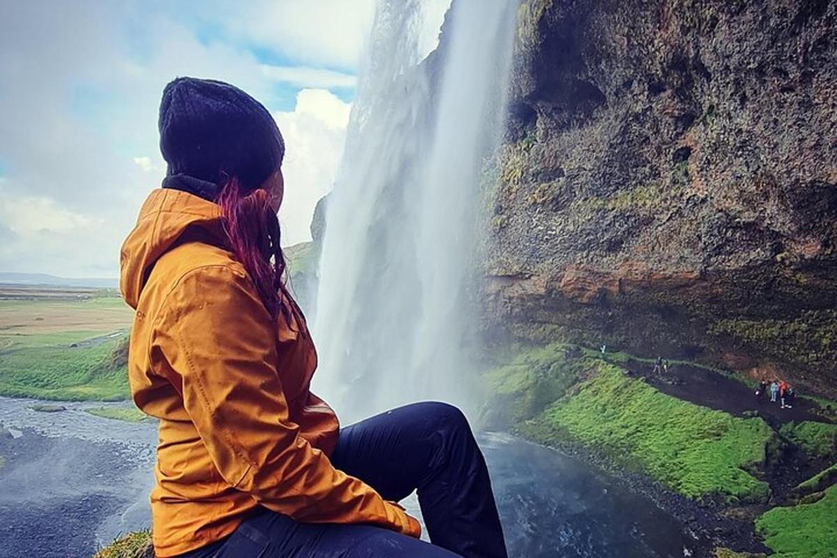 kona situr fyrir framan foss