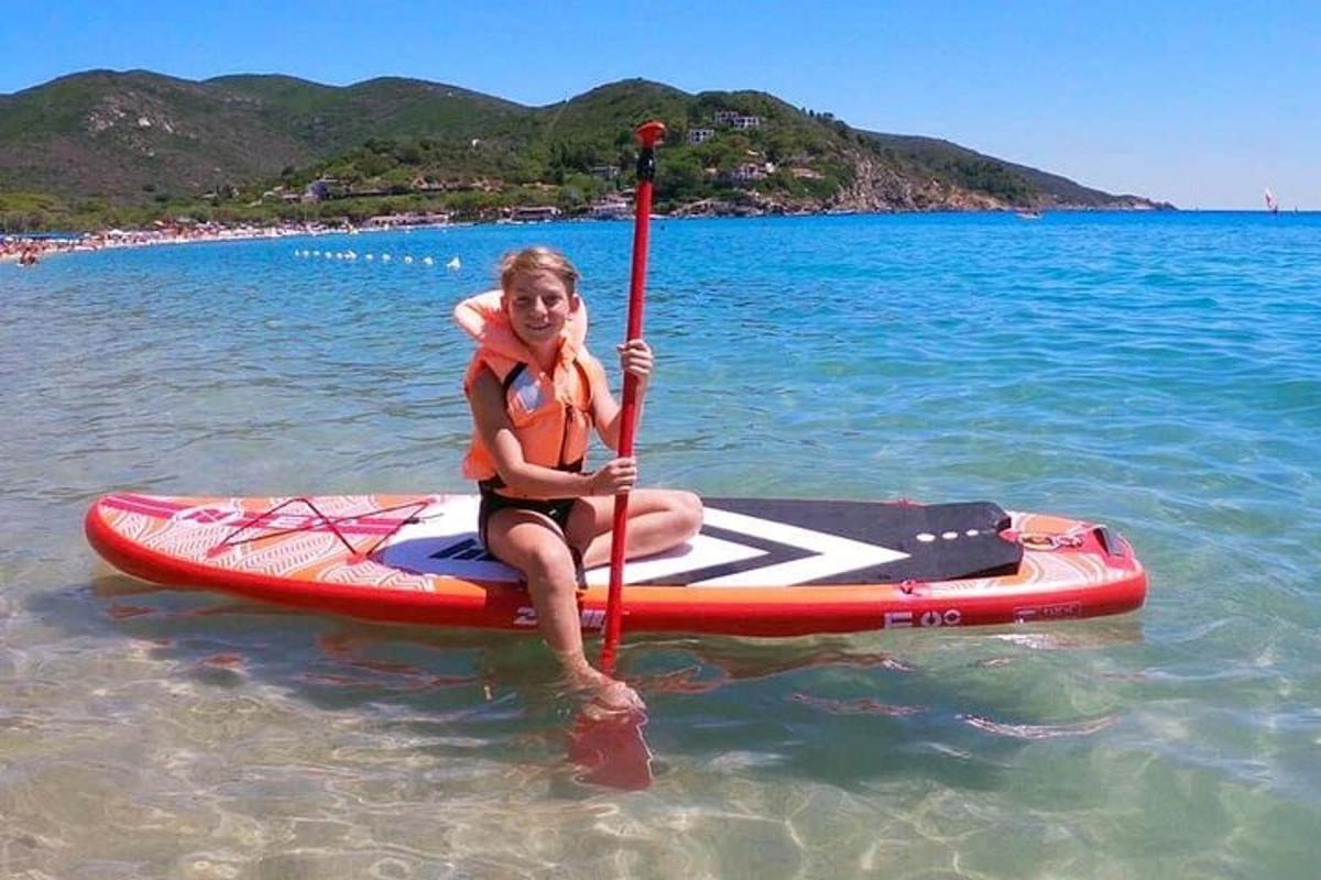 a woman sitting on a paddle board in the water