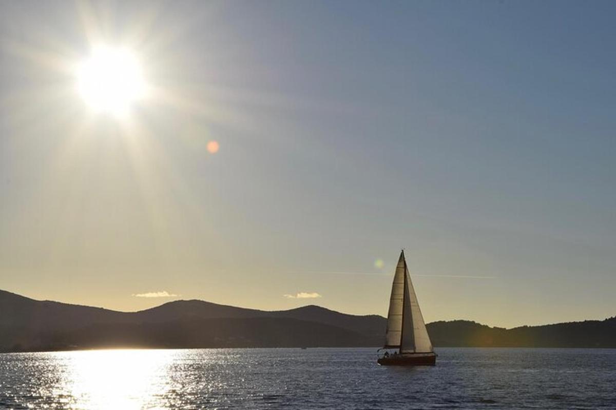 una barca a vela sull'acqua con il sole nel cielo