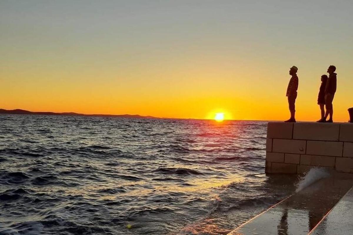 un gruppo di persone in piedi su un molo che guarda il tramonto