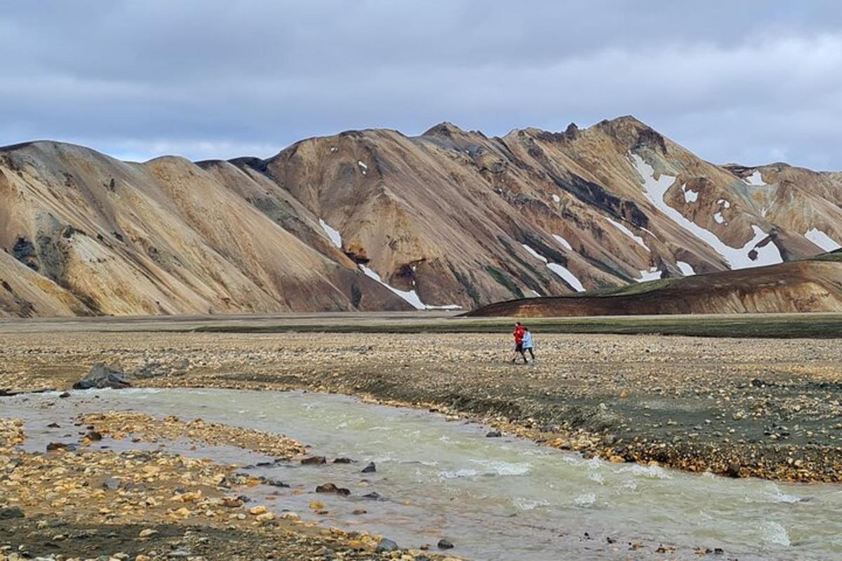 en person som står på et steinete jorde med fjell i bakgrunnen