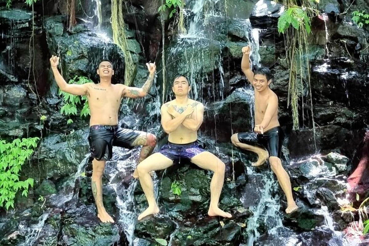 drie mannen zitten op rotsen voor een waterval