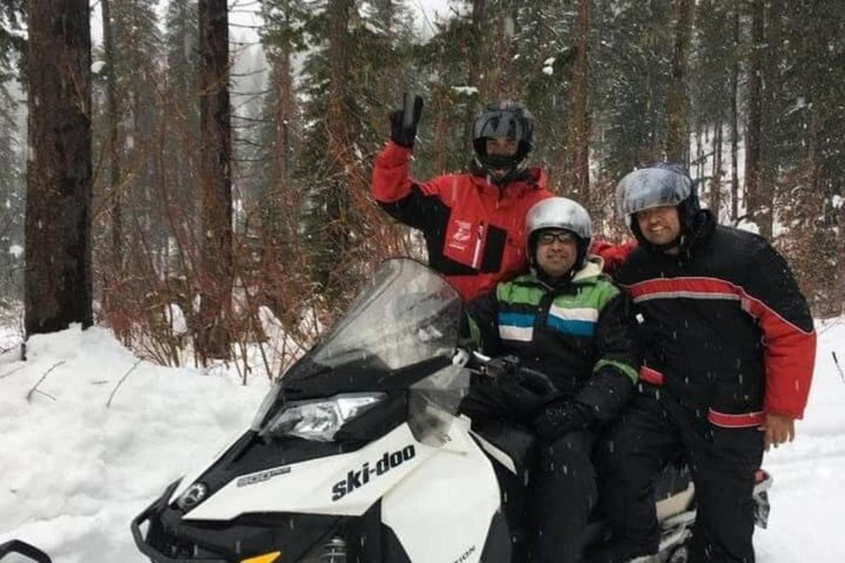 三个人坐在雪地摩托上