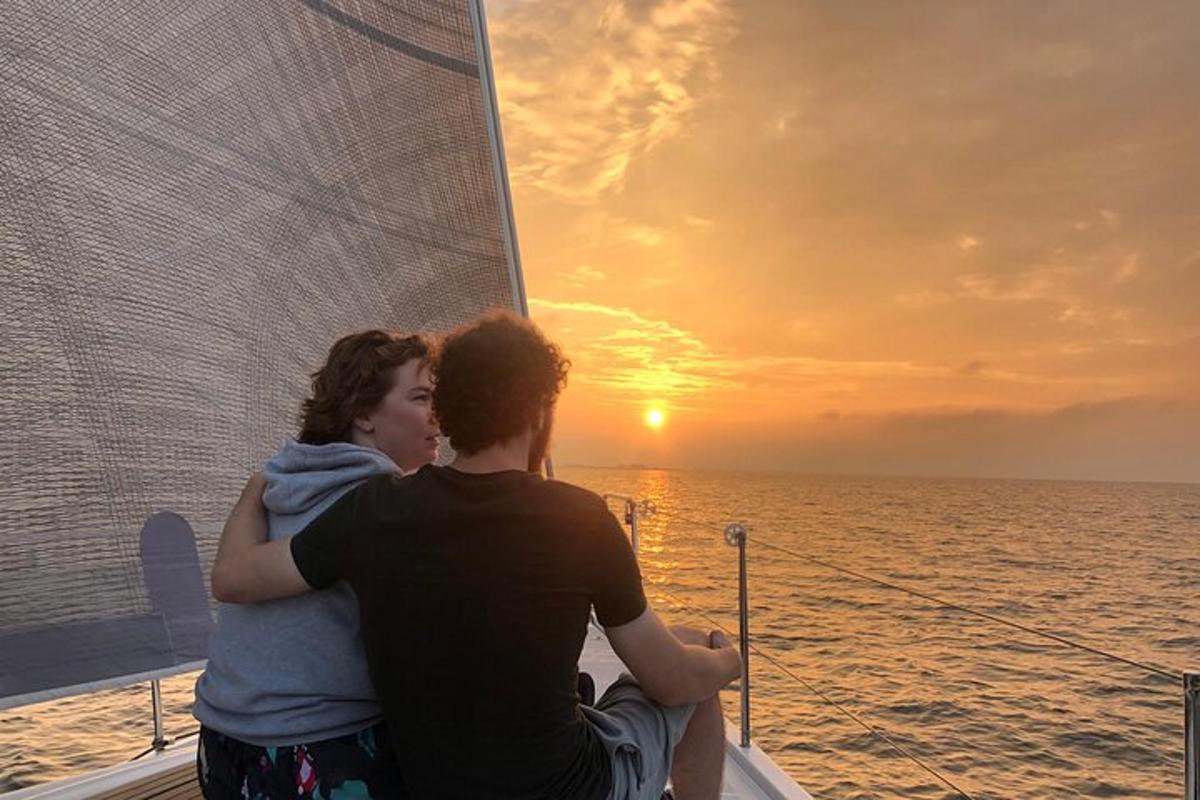 un uomo e una donna seduti su una barca che guardano il tramonto