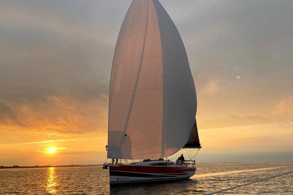 una barca a vela sull'acqua con il tramonto sullo sfondo