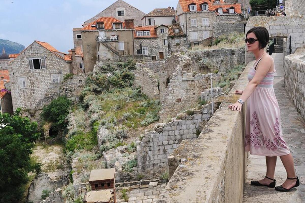 a woman standing on top of a wall looking at a city