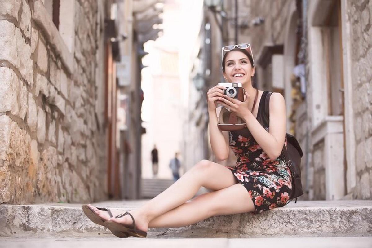 a woman sitting on a ledge taking a picture with a camera