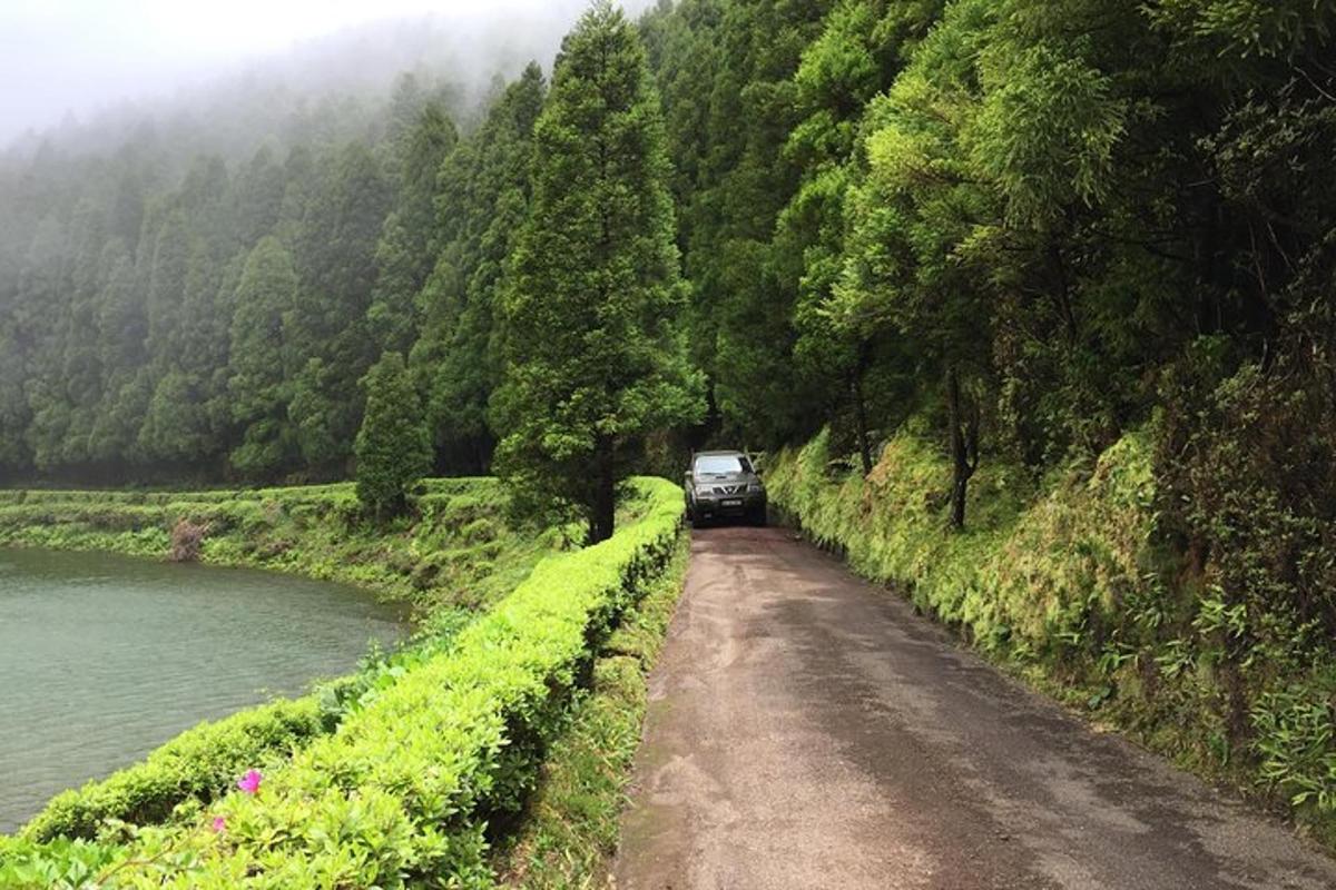 um caminhão dirigindo por uma estrada de terra ao lado de um rio