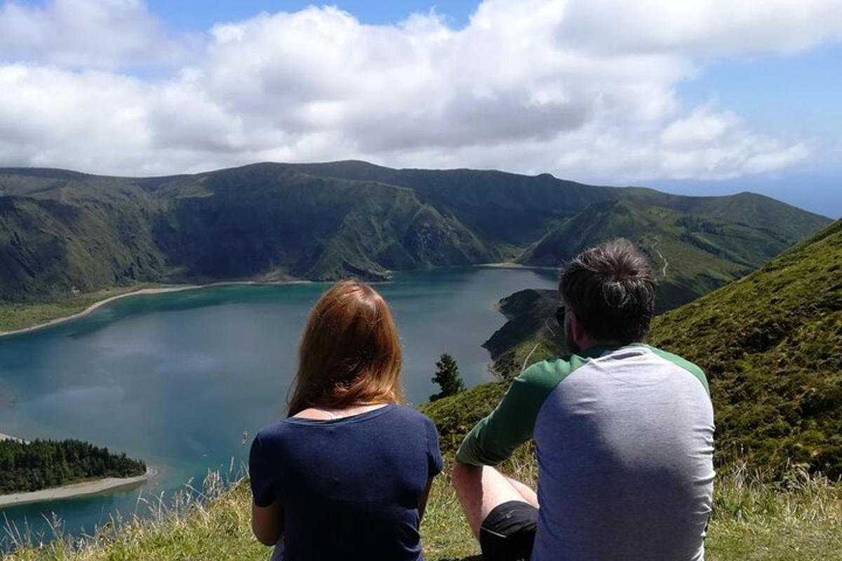 dva lidé sedící na kopci a dívající se na jezero
