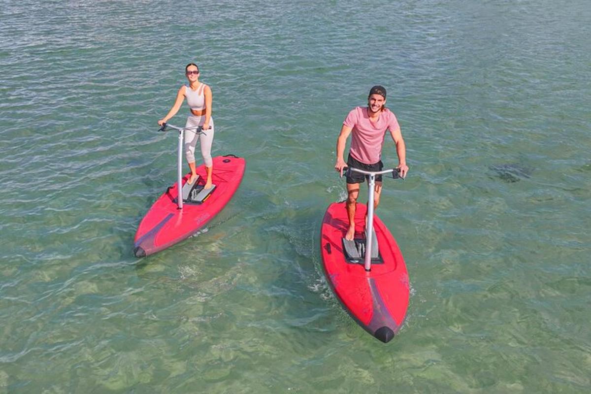 zwei Personen stehen auf roten Surfbrettern im Wasser