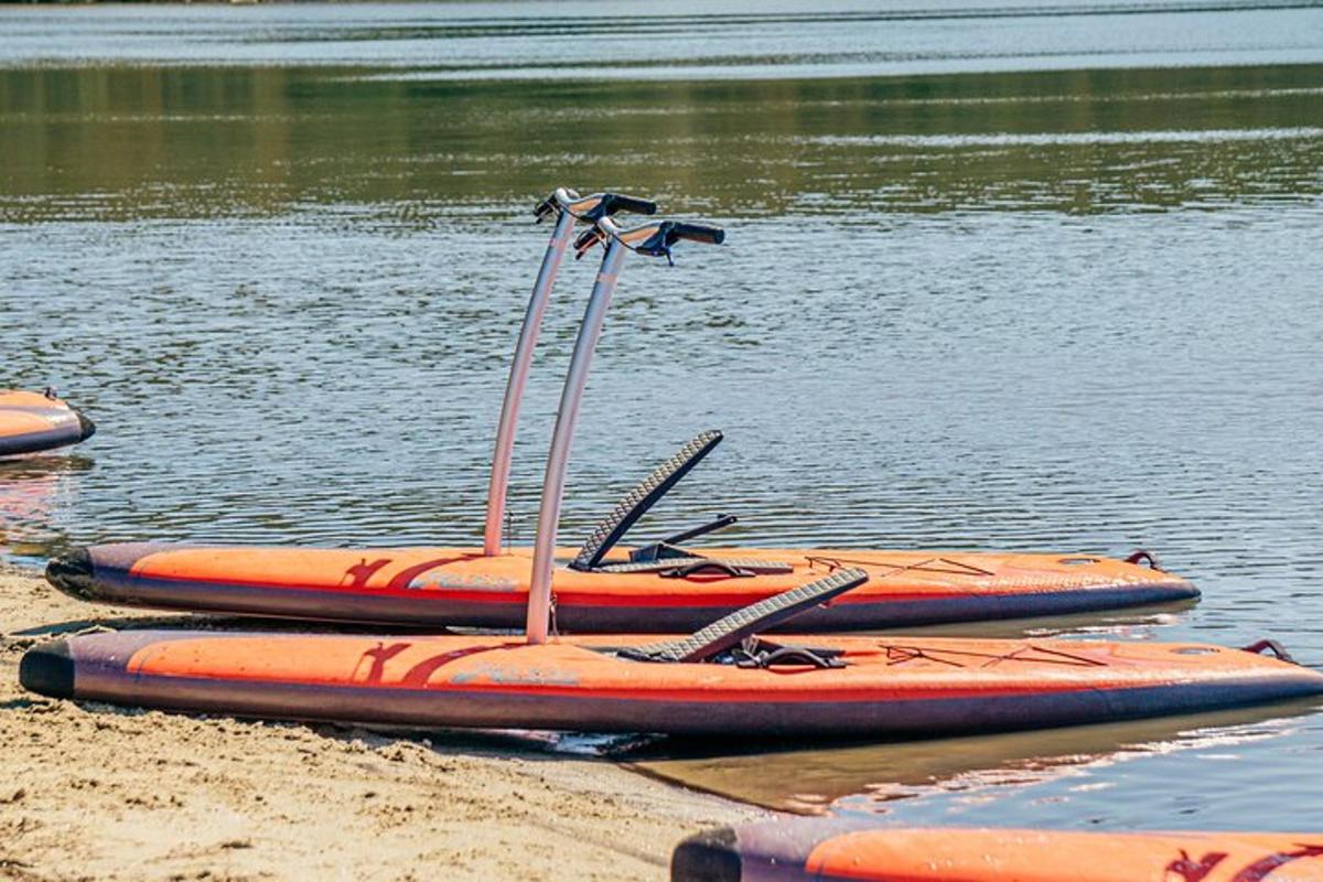 drei orangefarbene Kajaks am Ufer eines Sees