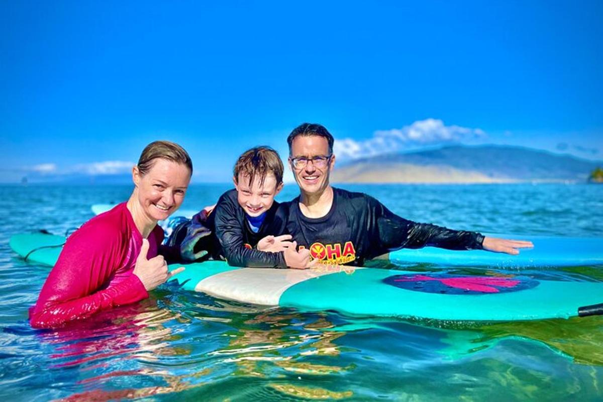 un bărbat, o femeie și un copil pe o placă de surf în apă