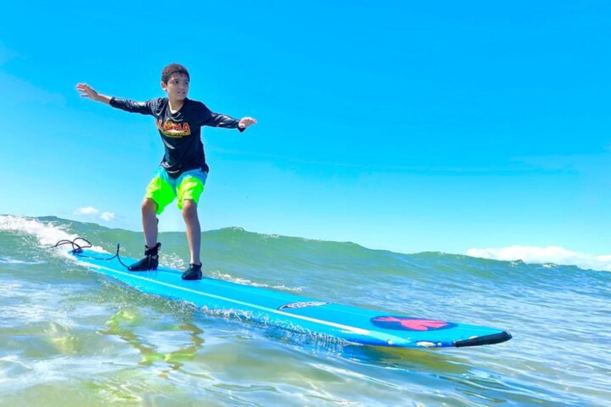 un băiat tânăr călărind un val pe o placă de surf în ocean