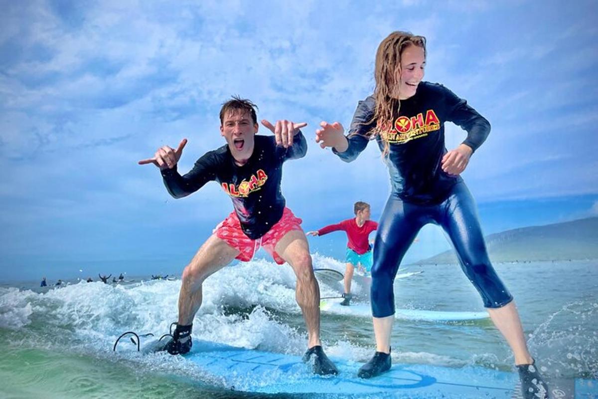 Două persoane călărind un val pe plăci de surf pe plajă