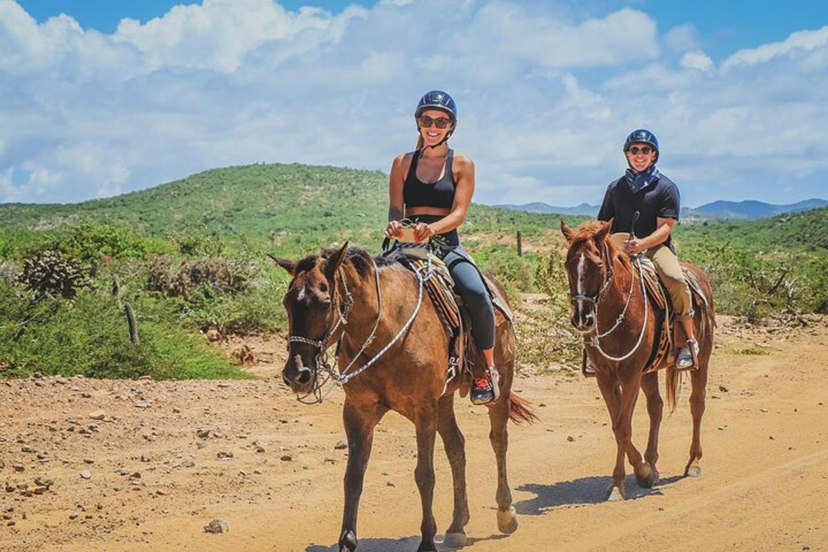 two people riding horses on a dirt road
