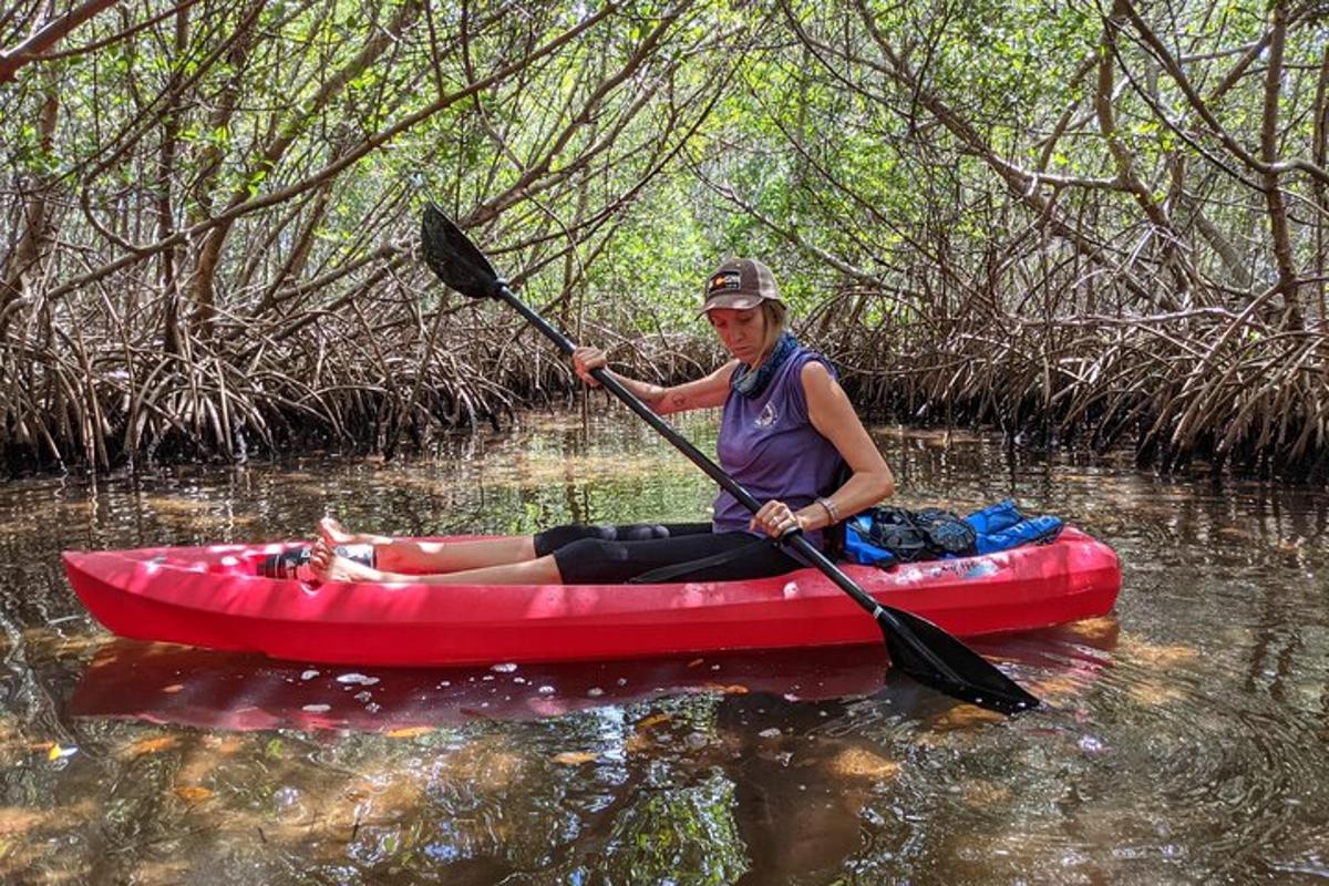 một người phụ nữ ngồi trên chiếc thuyền kayak màu đỏ dưới nước